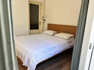 a small bedroom with a bed with white sheets at 2 bedroom near Dafni metro in Athens