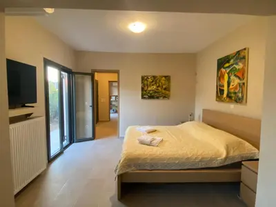 a bedroom with a bed and a flat screen tv at EUPHORIA Pool Villa in Porto Rafti
