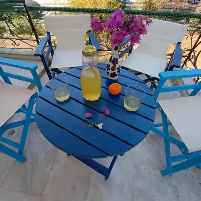 a blue table with a bottle of orange juice and two glasses at Sunlit and cosy apartment in Athens
