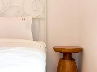 a bed with a wooden stool next to a bed at Bright & Airy Flat in Voula Center in Athens