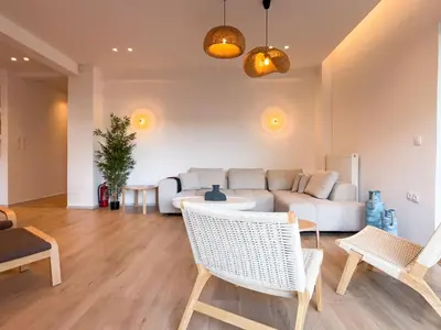 a living room with a couch and a table and chairs at Bright & Airy Flat in Voula Center in Athens