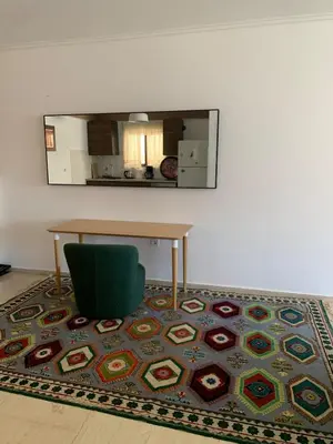 a room with a table and a green chair and a rug at Cozy house near the sea in Athens