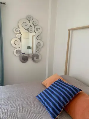 a mirror hanging on a wall above a bed at Cozy house near the sea in Athens