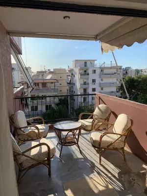 a patio with chairs and a table on a balcony at Cozy house near the sea in Athens