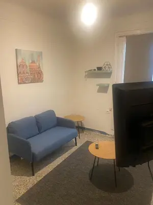 a living room with a blue couch and a tv at Center Hilton Area in Athens
