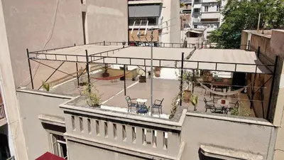 a balcony with chairs and tables on top of a building at Classic Athenian apartment in Athens