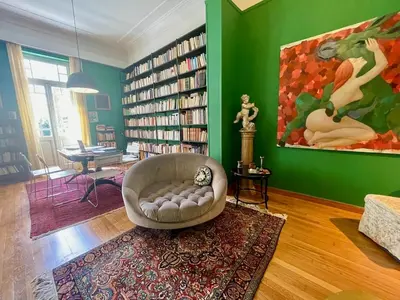 a living room with a chair and bookshelves at Classic Athenian apartment in Athens