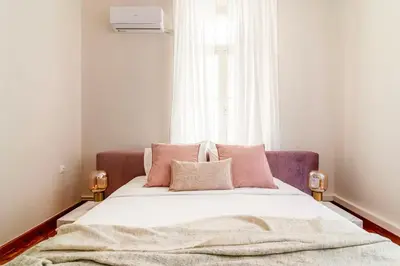 a bedroom with a bed with pink pillows and a window at Acropolis 1910s Neoclassical Gem Marble Bathrooms in Athens