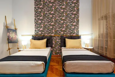 two beds in a room with a floral wall at Rebel's Rest - 4BR Apartment in Athens
