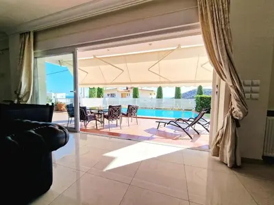 a living room with a sliding glass door with a table and chairs at Ethea in Anavissos