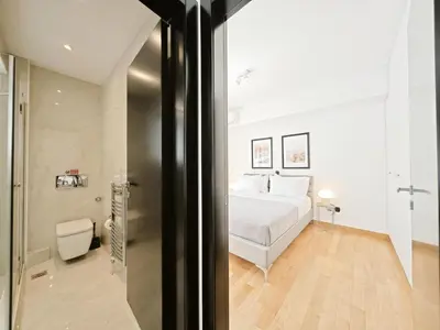 a bedroom with a white bed and a bathroom at Voula Private Pool, Beach, Home cinema Apartment in Athens
