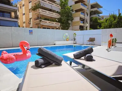 a swimming pool with two inflatable flamingos in the water at Voula Private Pool, Beach, Home cinema Apartment in Athens