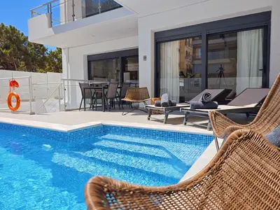 a swimming pool with wicker chairs next to a house at Voula Private Pool, Beach, Home cinema Apartment in Athens