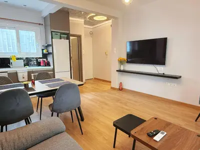 a living room with a table and a flat screen tv at Solvy Beachfront Suite-Direct to City Center & Piraeus Port & Airport in Athens
