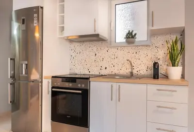 a kitchen with a stainless steel refrigerator and white cabinets at Joo Nest - Your home near Piraeus Port in Piraeus