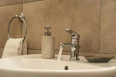 a bathroom sink with a faucet and a soap container at Joo Nest - Your home near Piraeus Port in Piraeus