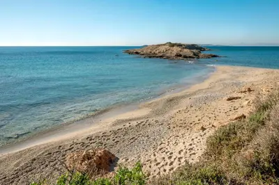 a sandy beach next to a body of water at Paradise Beachfront Villa Athenian Riviera in Aghia Marina
