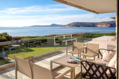 a patio with a table and chairs and the ocean at Paradise Beachfront Villa Athenian Riviera in Aghia Marina