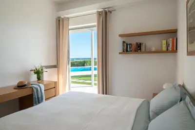 a bedroom with a bed and a sliding glass door at Paradise Beachfront Villa Athenian Riviera in Aghia Marina