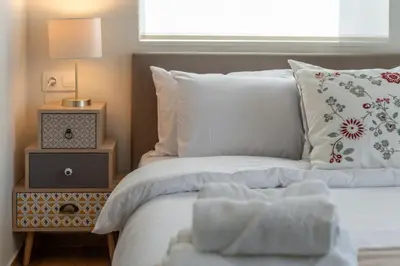 a bed with white sheets and a nightstand with a lamp at Aera Nest - 2BR, Alimos in Athens