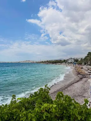 a beach with chairs and the ocean on a cloudy day at Aphrodite Apartment in Athens