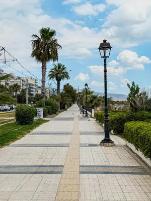 a sidewalk with a street light and palm trees at Aphrodite Apartment in Athens