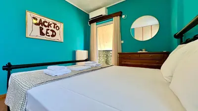 a bedroom with a bed with blue walls and a mirror at Seaside Central 3bdr Apt with sea views in Athens