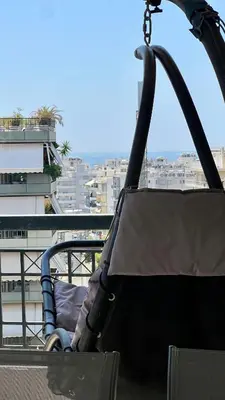 a person sitting in a swing on a balcony at Seaside Central 3bdr Apt with sea views in Athens