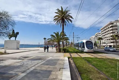 a train traveling down a street with a palm tree at Seaside Central 3bdr Apt with sea views in Athens