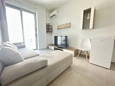 a white living room with a couch and a tv at Minimal City Retreat in Western Athens in Athens