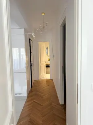 a hallway with white walls and wooden floors and a white door at The Kallion Kolonaki Athens in Athens