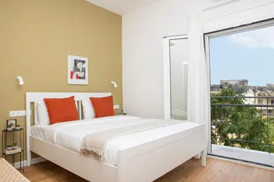 a bedroom with a white bed and a large window at Livinn Acropolis View in Athens