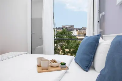 a white bed with two pillows and a tray with plants at Livinn Acropolis View in Athens