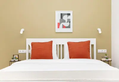 a bedroom with a white bed with two orange pillows at Livinn Acropolis View in Athens