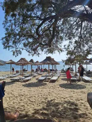 a beach with lounge chairs and umbrellas and the ocean at Christiana Luxury Apartments in Palaiá Fókaia