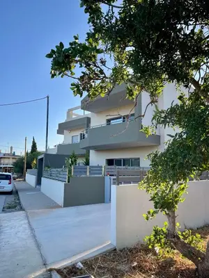 a large white building with a tree in front of it at Christiana Luxury Apartments in Palaiá Fókaia