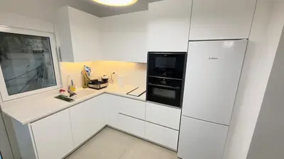 a kitchen with white cabinets and a black refrigerator at Filellinon in Athens