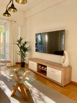 a living room with a tv and a glass table at Kypseli Modern Nest in Athens