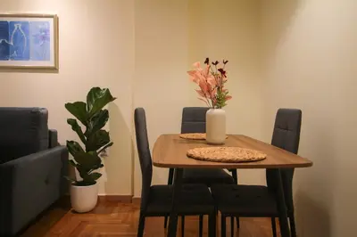 a dining room table with chairs and a vase with flowers on it at The Athenian Hive in Athens