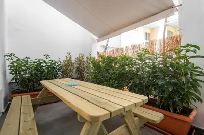 a wooden picnic table on a balcony with plants at 2BR Designer Apt Near Metro With Private Garden in Athens