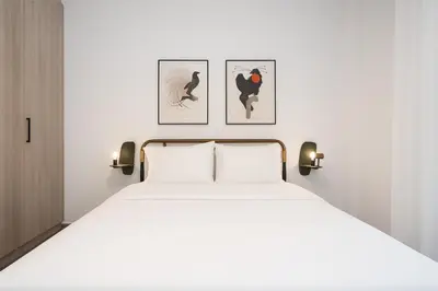 a bedroom with a white bed with three pictures on the wall at 2BR Designer Apt Near Metro With Private Garden in Athens