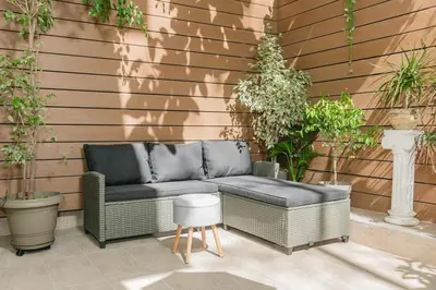 a wicker couch sitting on a patio with plants at Plantaea Deluxe Studio - Athens Modern Escape in Athens