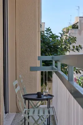 a table and chairs on the balcony of a building at Athens Glow 2bd Apt in Ilisia in Athens