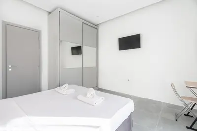 a white room with a bed and a chair at Εξαιρετικό διαμέρισμα στη Γλυφάδα in Athens