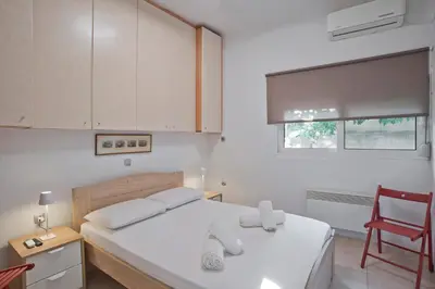 a bedroom with a white bed and a red chair at The Little House at Moschato 1BR, WiFi, AC in Piraeus