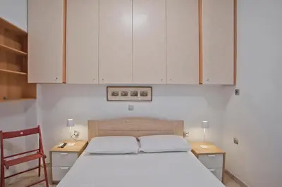 a bedroom with a white bed and wooden cabinets at The Little House at Moschato 1BR, WiFi, AC in Piraeus