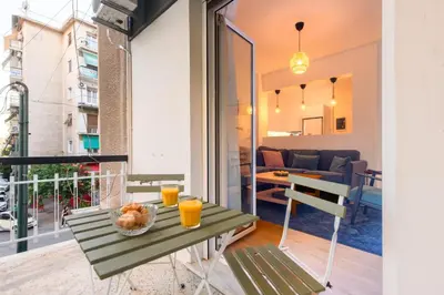 a table and chairs on a balcony with a living room at Elegant 3BDR Apt in Koukaki Near Acropolis in Athens