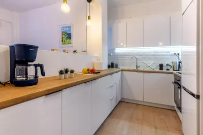 a kitchen with white cabinets and a wooden counter top at Elegant 3BDR Apt in Koukaki Near Acropolis in Athens