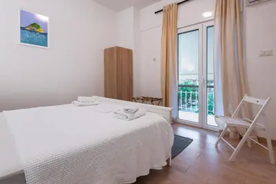 a white bedroom with a bed and a balcony at Elegant 3BDR Apt in Koukaki Near Acropolis in Athens