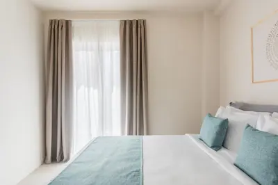 a bedroom with a bed with blue pillows and a window at Link by Zoia Living in Athens